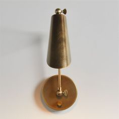 a wall light with a gold shade on it's side and a white background