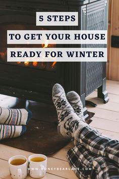 two people sitting in front of a fireplace with their feet up on the floor next to coffee