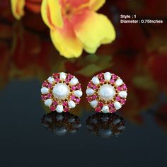 These Earrings are miniature flower-shaped studs with pearl and Semiprecious ruby stones - perfect for daily use or a special outing. They are specifically designed in 22 carat gold plating. This earring is perfect, comfortable, and attractive. You are bound to receive compliments, as this is one of the many other glamorous products created from the house of Indian Designs. Elegant White Ruby Earrings, White Ruby Round Earrings, White Gemstone Bridal Earrings For Gift, White Gemstone Bridal Earrings As Gift, White Gemstone Round Bridal Earrings, Round Ruby Bridal Earrings Gift, Earrings Studs Gold, Pearl Earrings Studs, Indian Designs