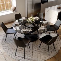 a round glass table with black chairs and white plates on it in the middle of a kitchen