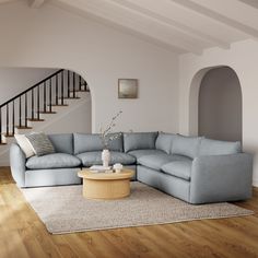 a living room with a blue sectional couch and coffee table in front of the stairs