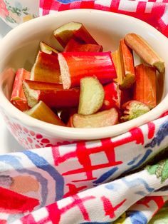 a white bowl filled with sliced up vegetables on top of a red and blue towel