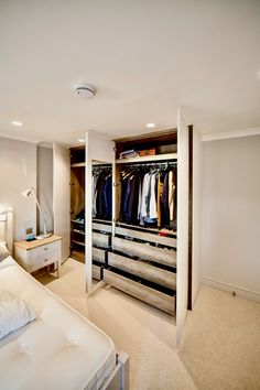 a bedroom with an open closet and white bed in the corner, along with two lamps on either side