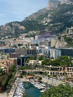 an aerial view of a city with boats docked in the water and mountains behind it