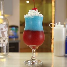 a colorful drink sitting on top of a table next to a bottle of booze