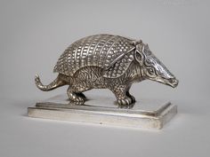 a silver figurine of an armadile on a metal base with a white background