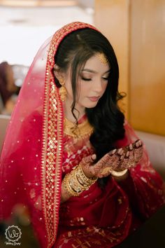 a woman in a red and gold bridal outfit is holding her hands out to the camera