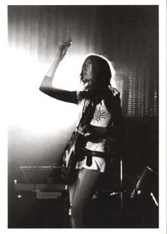 a black and white photo of a woman with her hand up in the air while singing