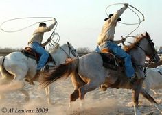 two men are riding horses with lassos in their hands and one man is holding on to the rope