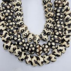 two strands of black and white beads on a white surface with holes in the middle