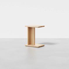 a small wooden table on a white surface with one leg raised up in the air