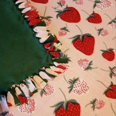 a green table cloth with red strawberries on it and white ruffles around the edges