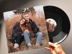 a person holding up a black vinyl record with an image of a couple on it