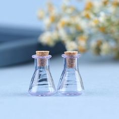 two glass bottles with cork tops sitting on a table