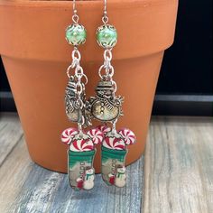 a pair of christmas themed earrings hanging from a potted plant