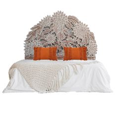 a bed with two orange pillows on top of it and an intricate headboard above the bed