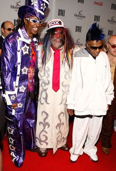 three men in costumes standing on a red carpet