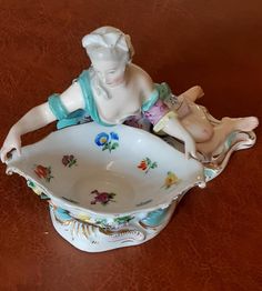 a porcelain figurine sitting on top of a bowl