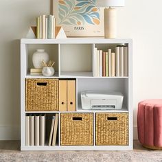 a white book shelf with baskets and books