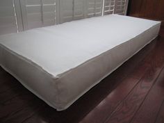 a white mattress sitting on top of a wooden floor