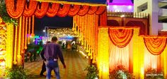 a man is walking through an archway decorated with flowers and garlands for a wedding