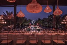 an outdoor dining area with tables and chairs, lit up by hanging lights at night