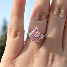 a woman's hand with a pink diamond ring on it