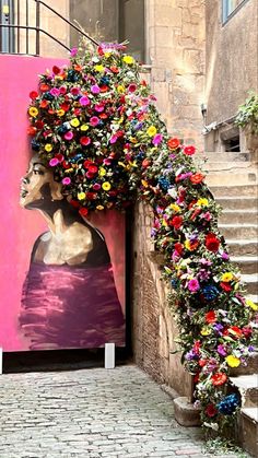 an art piece with flowers on it in front of a pink wall and steps leading up to the entrance