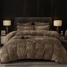 a bed with a brown comforter and two lamps on the nightstands next to it