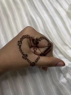 a woman's hand with henna tattoos on her fingers and heart shaped ring