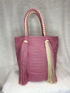 a pink handbag with tassels on it