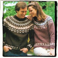 an older man and woman smile as they stand close together in knitted sweaters