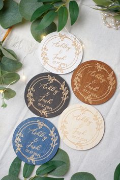 four wooden coasters sitting on top of a table next to leaves and greenery