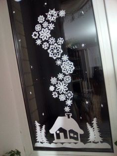 a window with snowflakes on it and a small house in the middle is shown