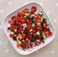 a white plate topped with cucumbers, tomatoes and other vegtables