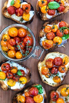 several pieces of bread with tomatoes and cheese on them, sitting on a wooden surface