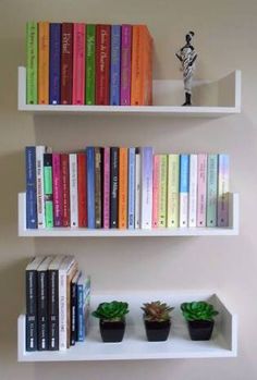 three white shelves with books and plants on them