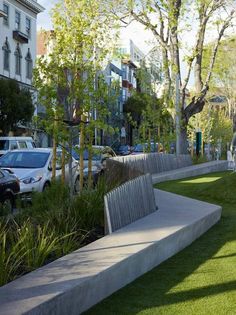 a park bench sitting in the middle of a grass covered area next to tall buildings