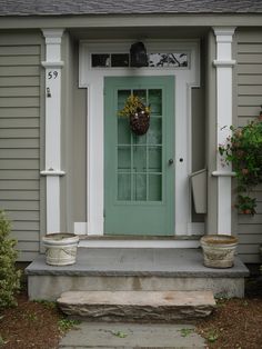 a green front door with two planters on the steps