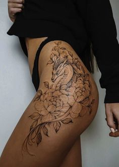 a woman's thigh with flowers and a dragon tattoo on the side of her leg