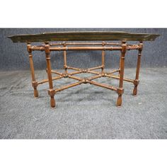 an old wooden table with bamboo legs and a tray on it's end shelf