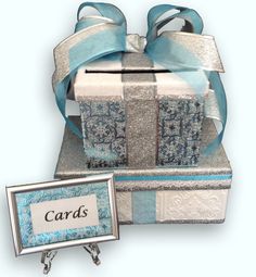 a gift box with a blue ribbon and some cards in it next to a card holder