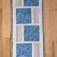 a blue and white quilted wall hanging on a wooden floor