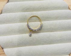 a pair of gold hoop earrings with diamonds on them sitting on a piece of fabric