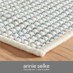 an area rug that is on the floor with text overlay reading annie selke fine cotton rugs, dark ash wood floors