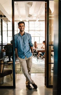 a man standing in an open doorway with his hands in his pockets and smiling at the camera