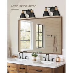 a bathroom vanity with two sinks under a large mirror and three lights above the sink