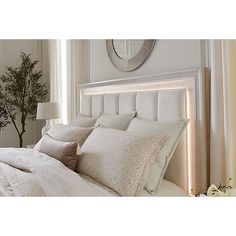 a bed with white sheets and pillows next to a mirror on the wall above it