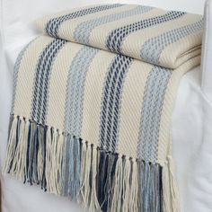 a blue and white striped blanket sitting on top of a couch next to a pillow