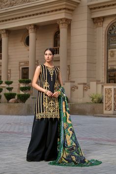 a woman standing in front of a building wearing a black and green outfit with gold details